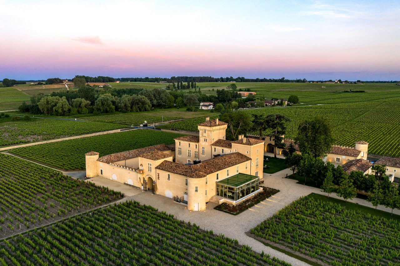 Vue aérienne d’un grand château bordelais entouré de vignes au crépuscule